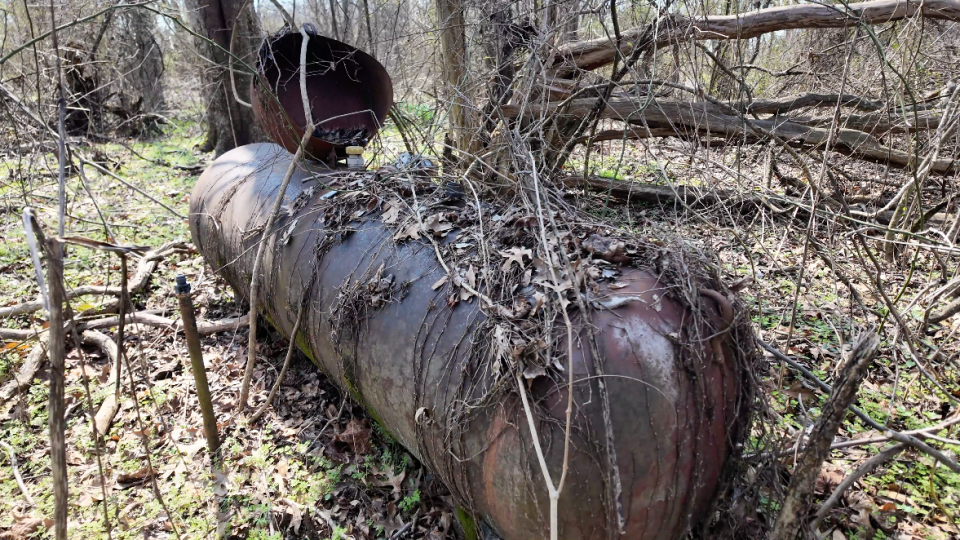 Rusty propane tank left abandoned in the yard.